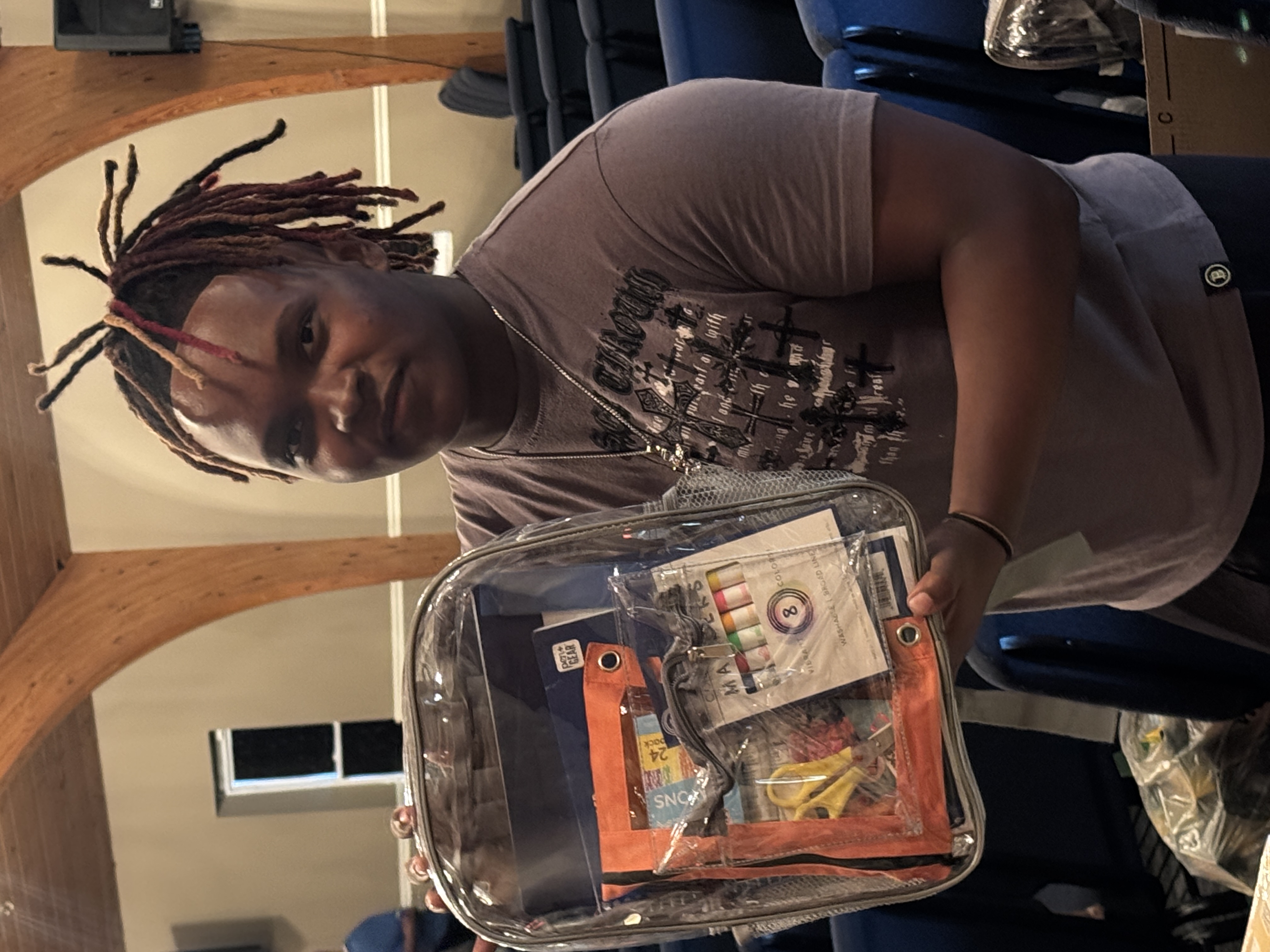 Youth participant holding a backpack filled with school supplies.